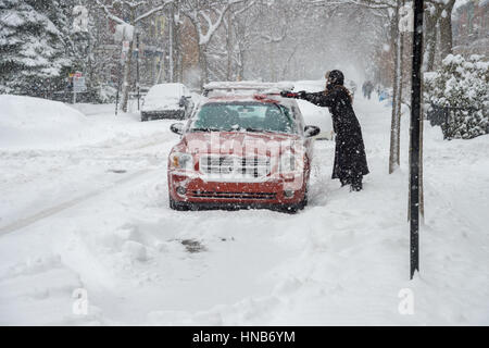 Montreal, CA - 29. Dezember 2016: Frau reinigen ihr Auto aus dem Schnee bei Schneefall im Winter. Stockfoto