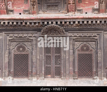 Komplizierte Lattic-Arbeit-Holzfenster und Türen eines alten Gebäudes in Bhaktapur, Kathmandu, geschnitzt im traditionellen Stil mit Hindu-Gottheiten Stockfoto