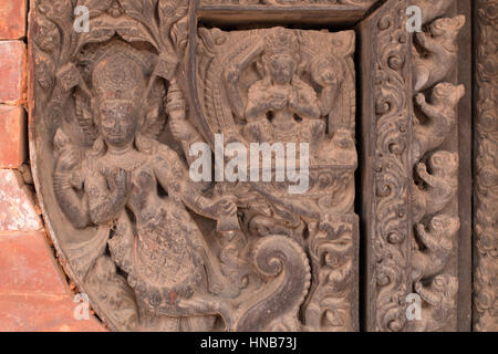 Holzschnitzerei von Hindu-Gottheiten und himmlische Nymphen schmücken die Wände eines Gebäudes in Bhaktapur, Kathmandu Stockfoto