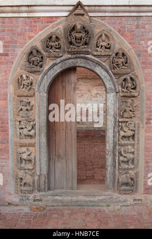 Hölzerner Torbogen mit aufwendigen Schnitzereien der Hindu-Götter und Göttinnen in Bhaktapur, Kathmandu geschmückt. Dies ist der Eingang zu einem Tempel Stockfoto