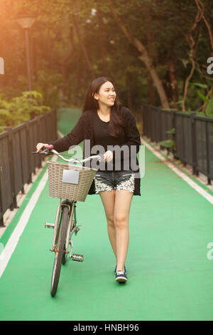 Hübsche Thai Girl führenden Fahrrad im Park Stockfoto