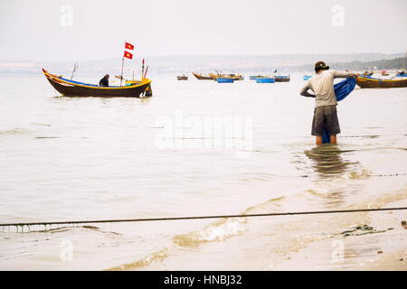 MUI NE, VIETNAM - Februar 7: Fischer mit bunten Fischerbooten am 7. Februar 2012 in Mui Ne, Vietnam. Stockfoto