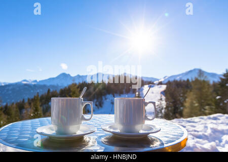 Zwei heiße Schokolade Becher auf der Terrasse eine Höhe in der Mountain Ski resort mit schönen sonnigen weißen Winter Hintergrund Stockfoto