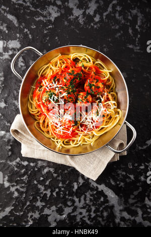 leckere Pasta Spaghetti mit Fleischbällchen und Tomatensauce und Parmesan-Käse auf einem dunklen Hintergrund in einer kleinen eisernen Pfanne Stockfoto