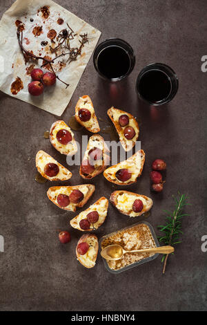 Rotwein und Vorspeise mit Häppchen mit Käse, Trauben, Wein, Honig und Brot auf einem Holztisch Stockfoto
