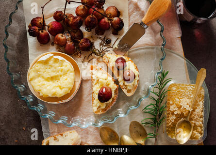 Gebackener Camembert mit Trauben und Honig. und Wein auf alten steinernen Hintergrund Stockfoto