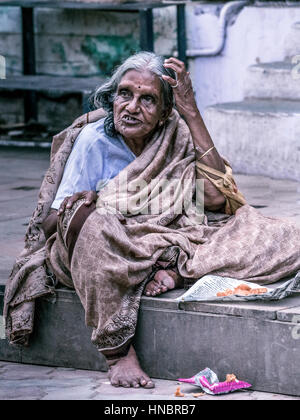 Madurai, Indien - 19. Oktober 2013: Eine alte ergrauten Dame sitzt auf dem Bürgersteig der Straße um Meenakshi Tempel. Sie hat einen ausdrucksstarken entlassenden fa Stockfoto