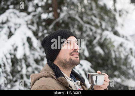 Mann im Schnee Tasse Tee trinken Stockfoto