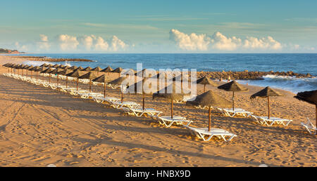 Liegestühle und Sonnenschirme am Strand, Algarve, Portugal Stockfoto