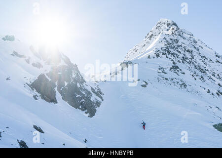 Skifahrer, Klettern auf einen steilen Hang, Tirol, Österreich Stockfoto