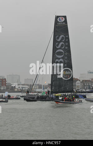 Alex Tomson anreisen in Gosport in England wird der Läufer oben in der Vendee Globe rund um die Welt-Regatta mit Flottille kleine Boote und große Menschenmenge auf der Ufer-Seite Stockfoto