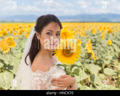 Schöne junge Braut posiert in einem Sonnenblumenfeld Stockfoto