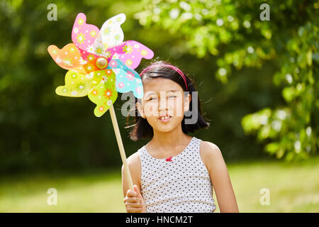 Asiatische Kind spielt mit Windmühle im Park im Herbst Stockfoto