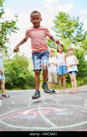 Afrikanischen jungen, Himmel und Hölle spielen und springen mit Ehrgeiz und Konzentration Stockfoto