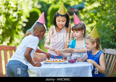 Viele Kinder zusammen feiern mit Geburtstagstorte bei Kids party Stockfoto