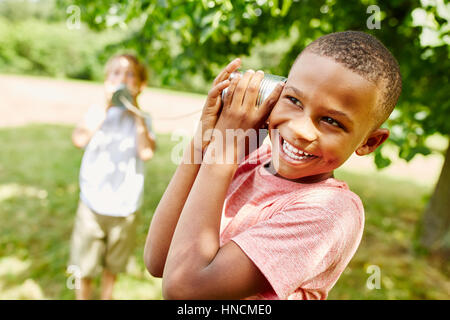 Afrikanischen jungen mit Blechdose Telefon mit Freund spielen Stockfoto