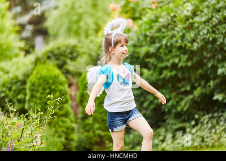 Mädchen im Garten wie Engel für Karneval verkleidet Stockfoto