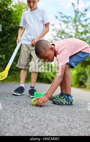 Zwei Kinder spielen Streethockey Ball im park Stockfoto