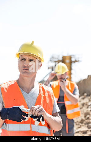 Nachdenklich Arbeiter stehend auf Baustelle mit Kollegen im Hintergrund Stockfoto