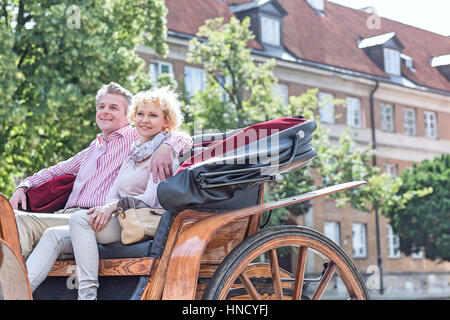 Glückliches Ehepaar mittleren Alters sitzen im Pferdewagen auf Stadtstraße Stockfoto