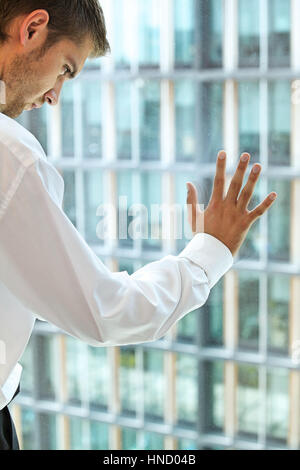 Junge Caucassian Geschäftsmann gegen Bürofenster Stockfoto