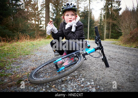 Ein junges Mädchen sitzt mit ihrem Fahrrad Essen einen Snack auf einen Waldweg Stockfoto