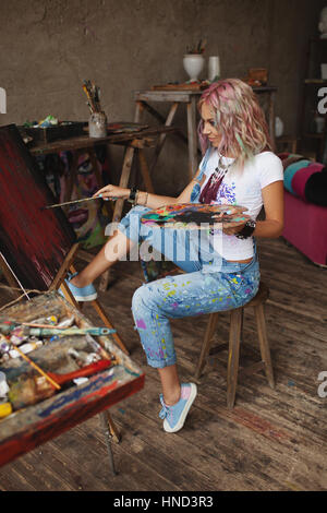 Malt der Künstler mit bunten Haaren Farbe befleckt jeans Stockfoto