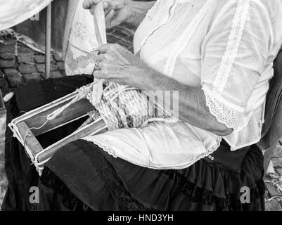 Ältere Dame baut Taschen mit den getrockneten Blättern der Maiskolben von Hand gewebt. Stockfoto