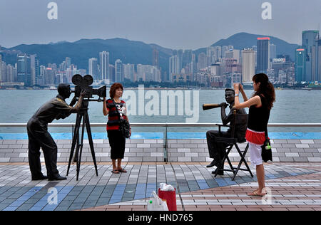 Touristen in Avenue of the Stars. Kameramann und Regisseur Statuen mit Victoria Harbour im Hintergrund, Hong Kong, China Stockfoto