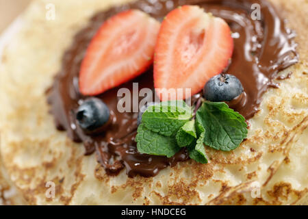 frische Blinis oder Plinsen geschmolzener Bitterschokolade und Beeren, Nahaufnahme Foto Stockfoto