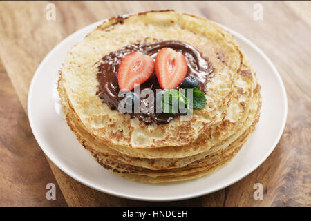 frische Blinis oder Plinsen geschmolzener Bitterschokolade und Beeren, flachen Fokus Stockfoto