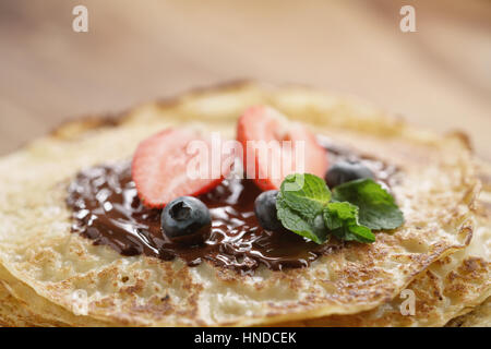 frische Blinis oder Plinsen geschmolzener Bitterschokolade und Beeren, Nahaufnahme Foto Stockfoto