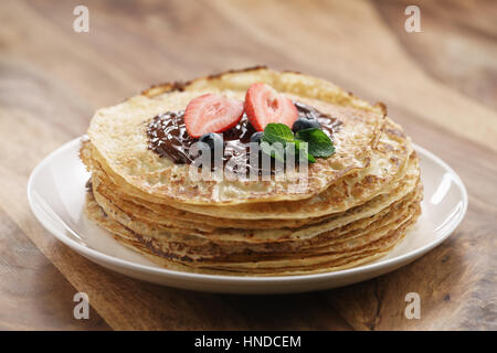 frische Blinis oder Plinsen geschmolzener Bitterschokolade und Beeren, flachen Fokus Stockfoto