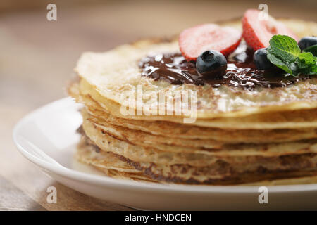 frische Blinis oder Plinsen geschmolzener Bitterschokolade und Beeren, Nahaufnahme Foto Stockfoto