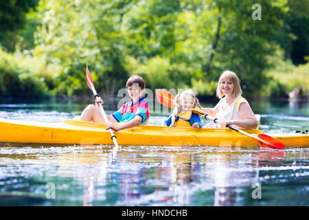 Glückliche Familie mit zwei Kindern Kajakfahrt auf schönen Fluss genießen. Mutter mit jungen Mädchen und Teenager Kajak an heißen Sommertag. Wasser-Sport-fu Stockfoto