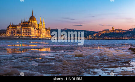 Eis auf der Donau in Budapest mit dem ungarischen Parlament und Königspalast auf beiden Seiten in der Dämmerung Stockfoto