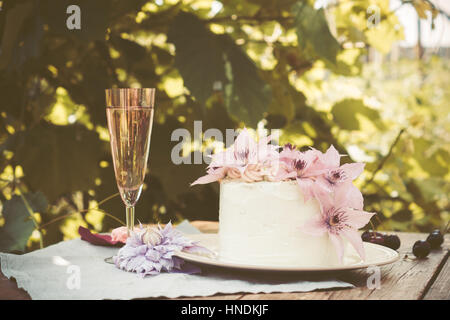 Cremige Kuchen mit Clematis Blumen auf dem Holztisch. Geringe Schärfentiefe. Stockfoto