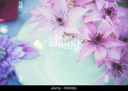 Cremige Kuchen mit Clematis Blumen auf dem Holztisch. Geringe Schärfentiefe. Stockfoto