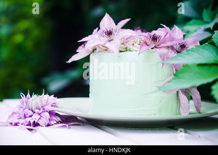 Cremige Kuchen mit Clematis Blumen auf dem Holztisch. Geringe Schärfentiefe. Stockfoto