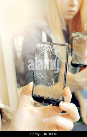 Das Mädchen schaut durch ein zerbrochenes Glas, weichen Lichteffekt Stockfoto
