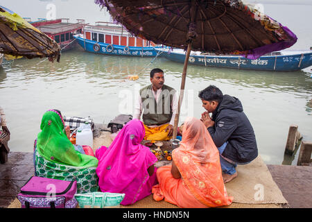 Pilger und ein Pandit (heiliger Mann und Priester, die Zeremonien durchführt) führt eine Puja (Gebet), auf den Ghats von Fluss Ganges, Varanasi, Uttar Pradesh, In Stockfoto