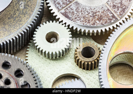 alte rostige Metallgetriebe und andere Details der Maschinen auf Messing-Hintergrund Stockfoto