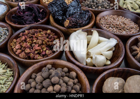 Schüssel mit Knoblauch unter Gewürze in Holzschalen Stockfoto