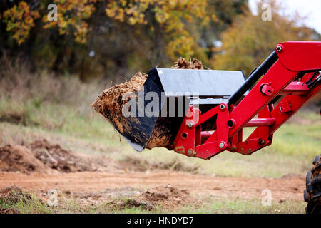 Roter Traktor Frontlader mit Schmutz auf Bau-Seite Stockfoto