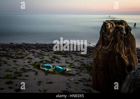 Schwimmbrille am leeren Strand, neben der Mole. Kurz vor Sonnenaufgang. Stockfoto