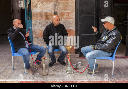 Straßenszene, genannt arabische Männer Nargila Wasserpfeife im Marktgebiet der Muristan Suq Aftimos, Altstadt, Jerusalem, Israel. Stockfoto