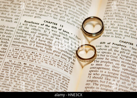 Zwei Eheringe in eine Bibel mit den Schatten, die Herzen Stockfoto