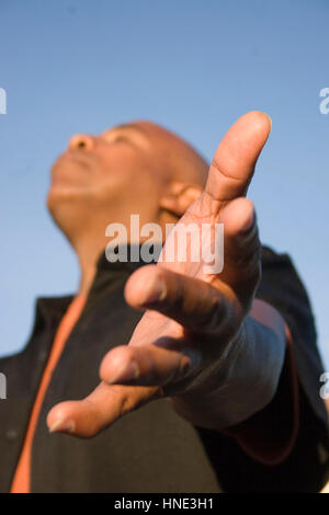 Afrikanische amerikanische Mann mit offenen Armen in tiefer Verehrung. Stockfoto