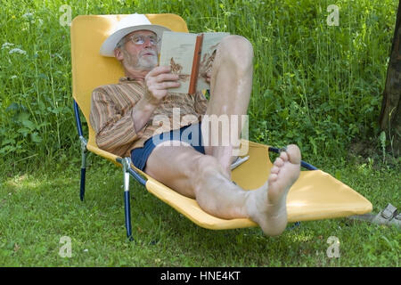 Model Release, Pensionist, 65 +, so Auf Liegestuhl Im Garten Und liest Ein Buch - Rentner auf einem Liegestuhl liegen und ein Buch zu lesen Stockfoto