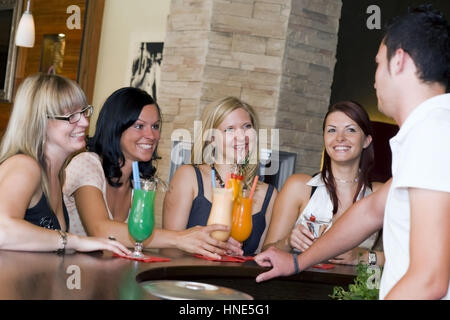 Model Release, Junger Kellner Flirtet Mit Vier Frauen eine der Bar - Barkeeper coquets mit vier Frauen an der bar Stockfoto